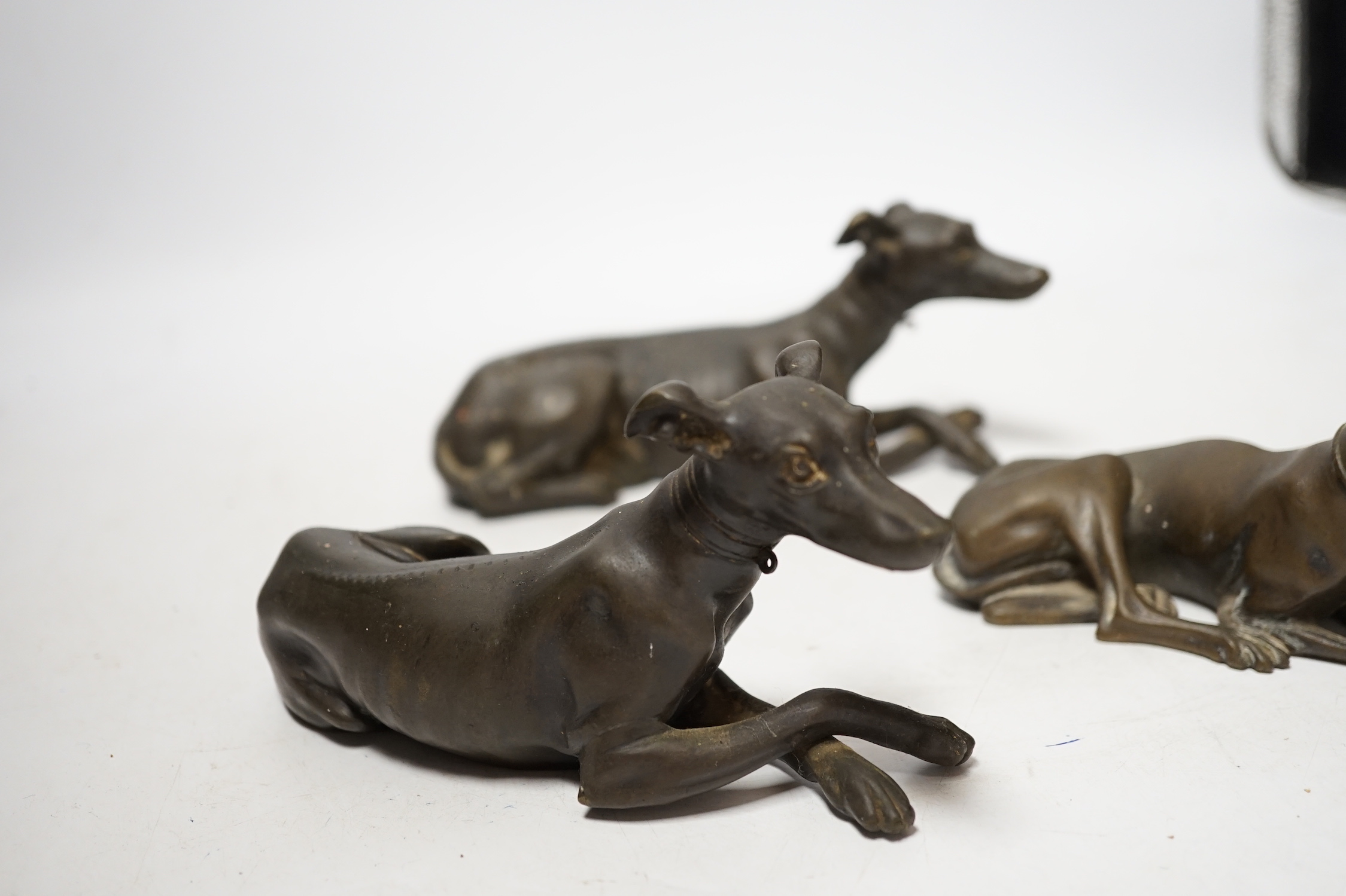 Three late 19th century bronze models of recumbent greyhounds, 17cm